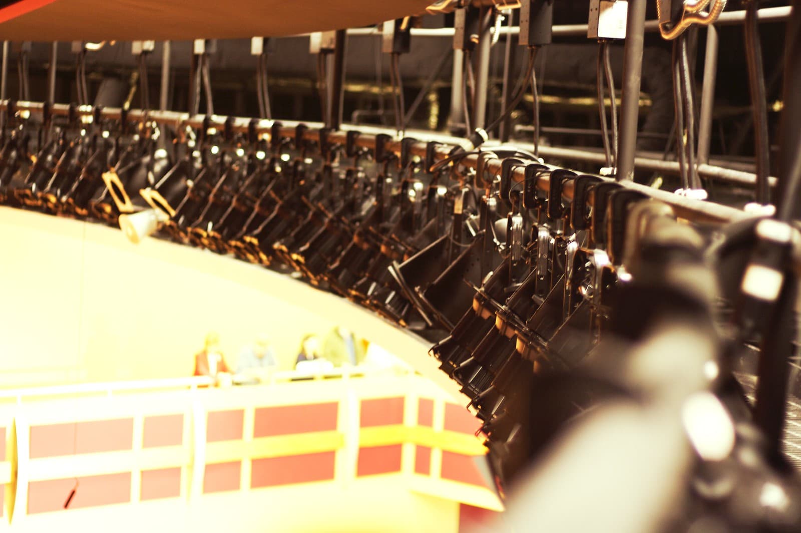 A row of theatrical stage lights glowing above a darkened stage.